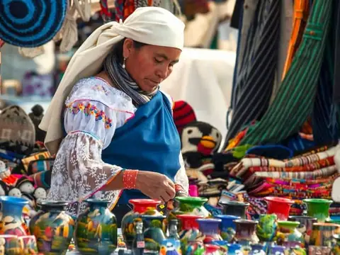 Otavalo artisan selling textiles and pottery at the market