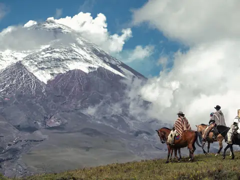 Horse riders on the páramo below a snow-capped volcano