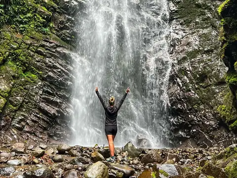 A traveler in front of a waterfall in Mindo Cloud Forest